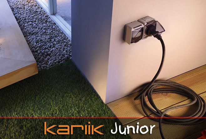 Podwójne gniazdo z klapką Karlik Junior zamontowane na zewnątrz budynku przy tarasie z podłączonym przedłużaczem.